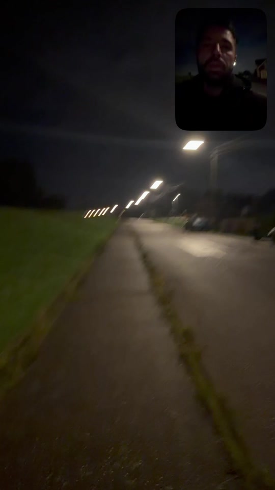 A quiet road and sidewalk under streetlights at night, with Eduard in a small selfie inset.
