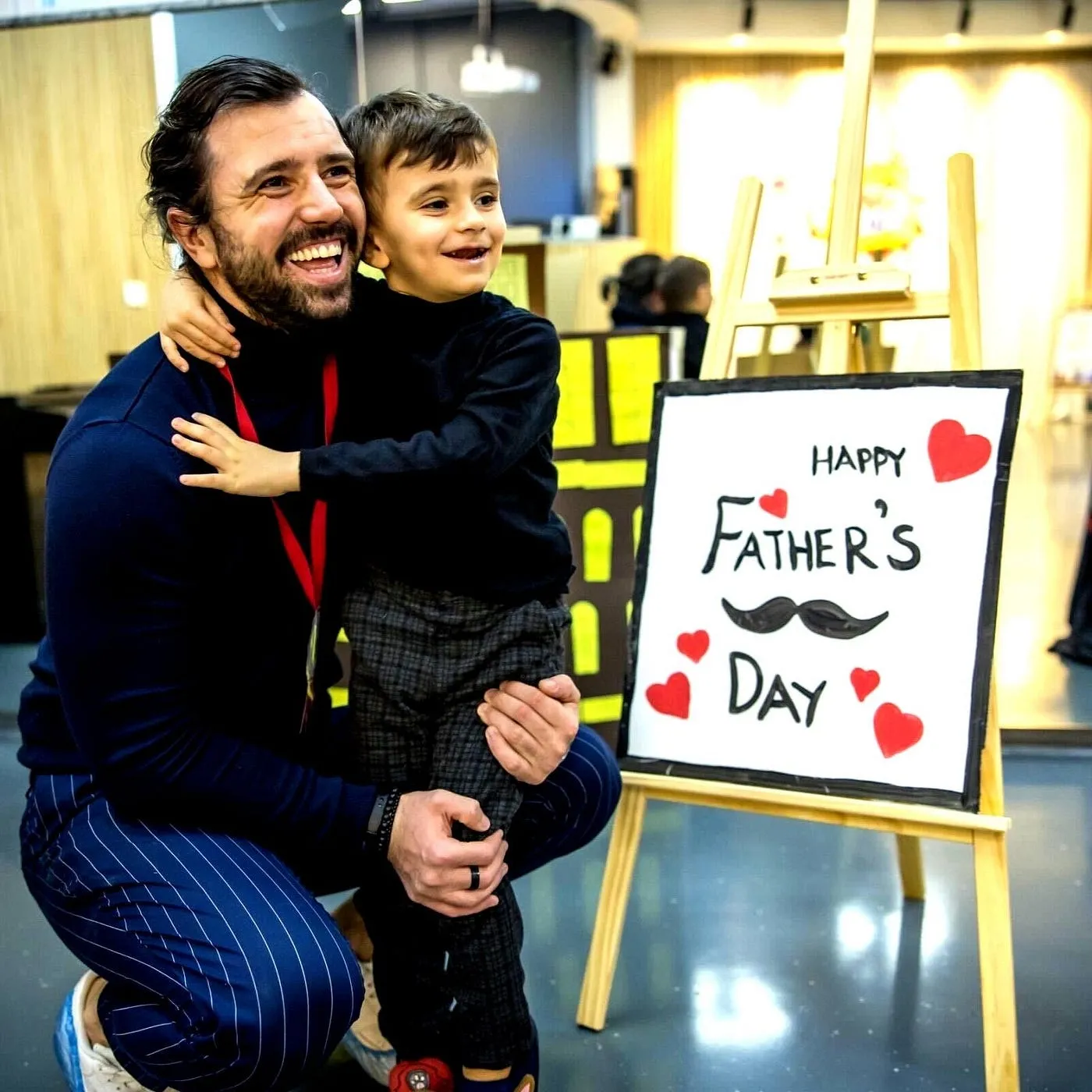 Father and son embracing beside a hand-painted Happy Father's Day sign