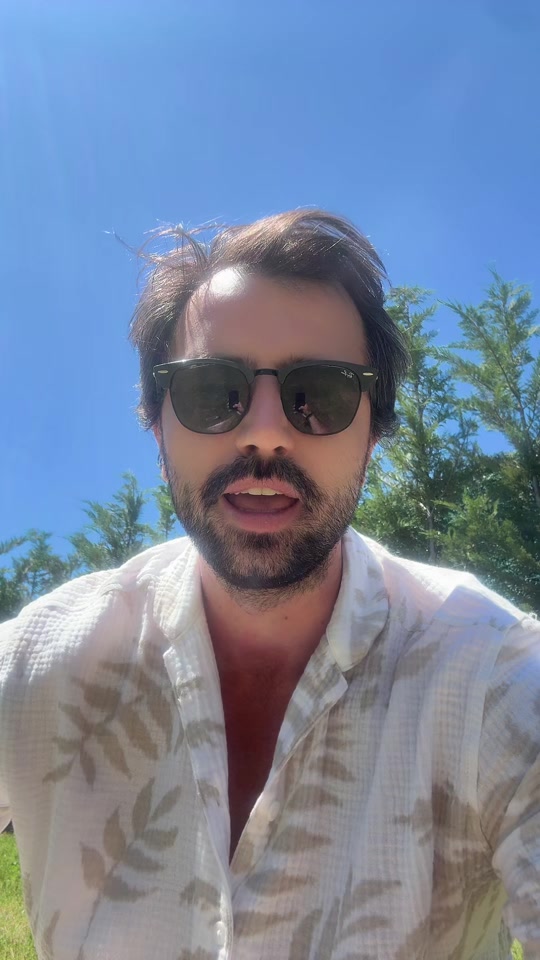 Eduard outdoors in sunglasses and a light patterned shirt, beneath a blue sky.