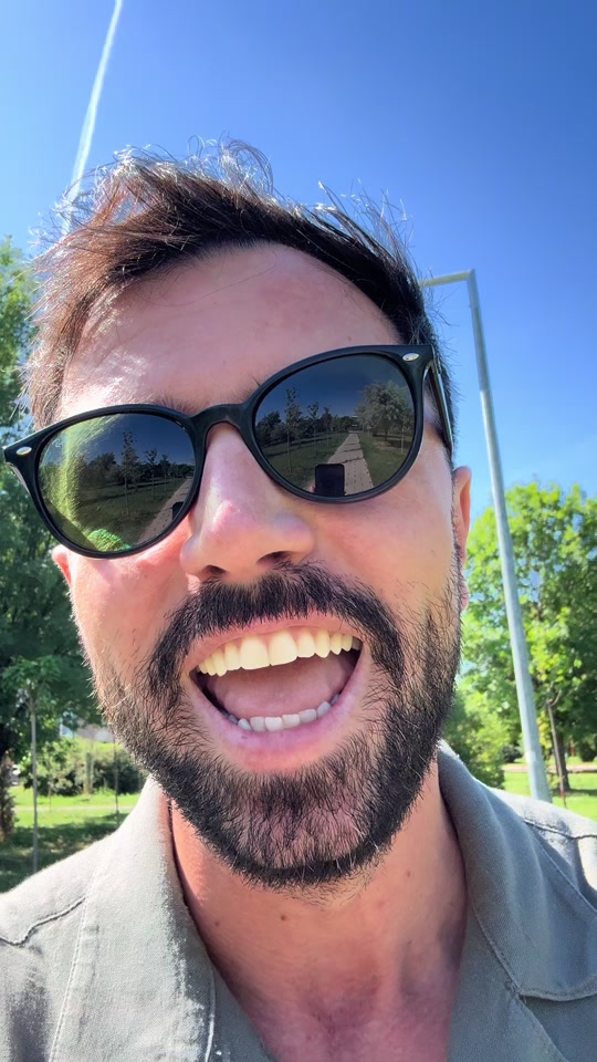 Eduard speaking outdoors in sunglasses, with a tree-lined path reflected in the lenses.