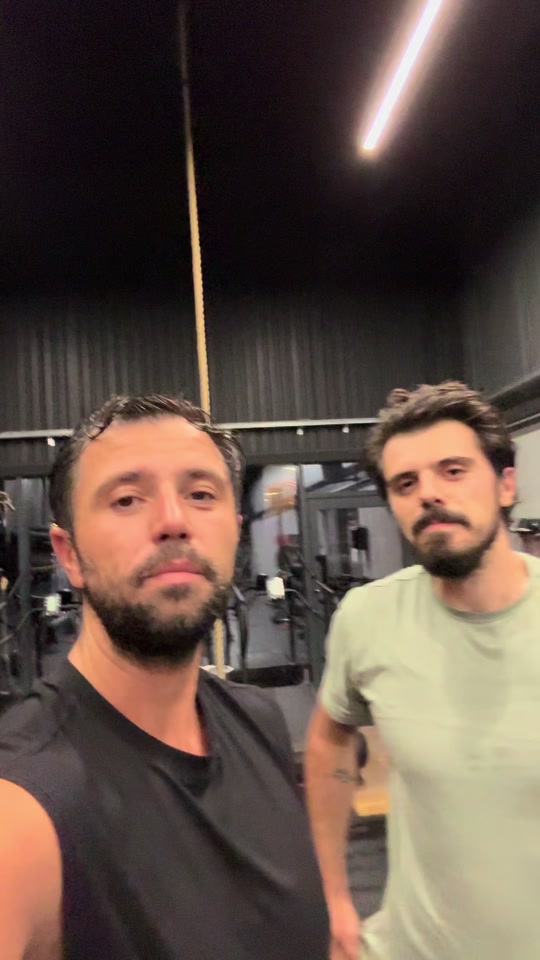 Eduard in a black training vest beside a friend in a light green T-shirt inside a gym.