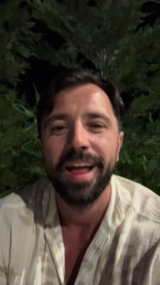 Eduard outside at night with leafy branches behind him, in the original video about a question for God.