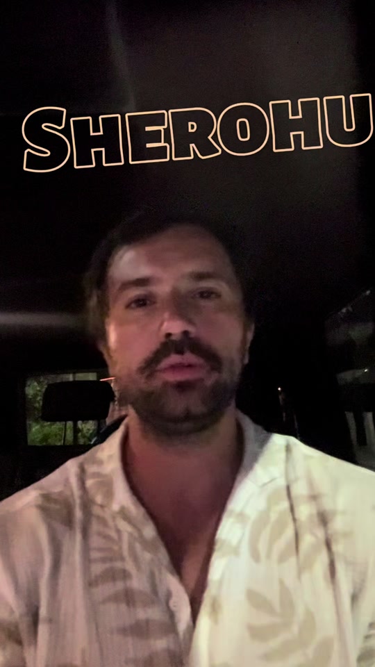 Eduard speaking inside a car at night, with the original Albanian word “SHEROHU” above him.
