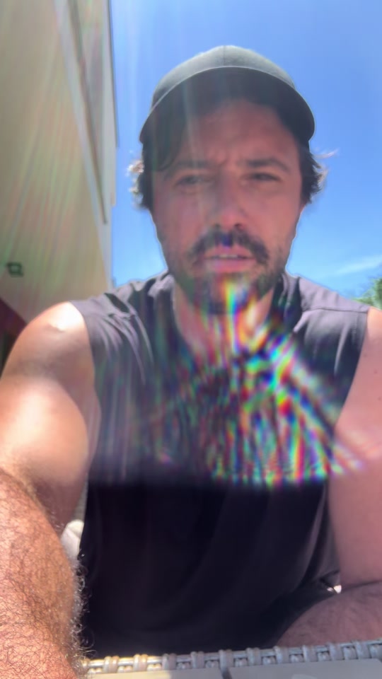 Eduard Luta speaking outdoors in a black sleeveless shirt and cap.