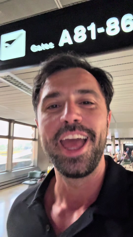 Eduard Luta speaking at an airport beneath a gates sign.