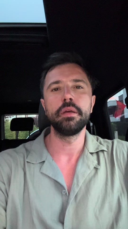 Eduard wearing a light green shirt, speaking inside a car about communicating with a sick family member.
