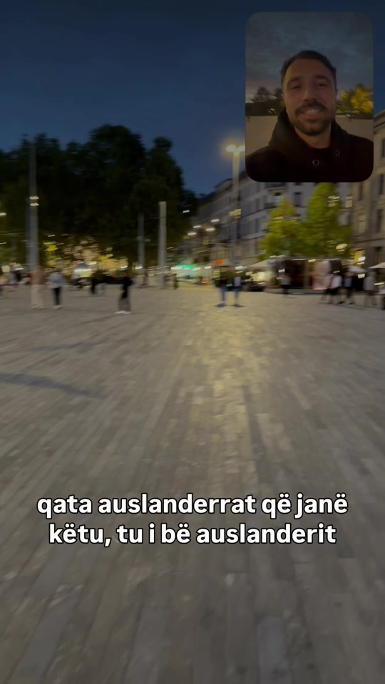 An evening pedestrian square, with Eduard speaking in a small inset and Albanian subtitles across the original video thumbnail.
